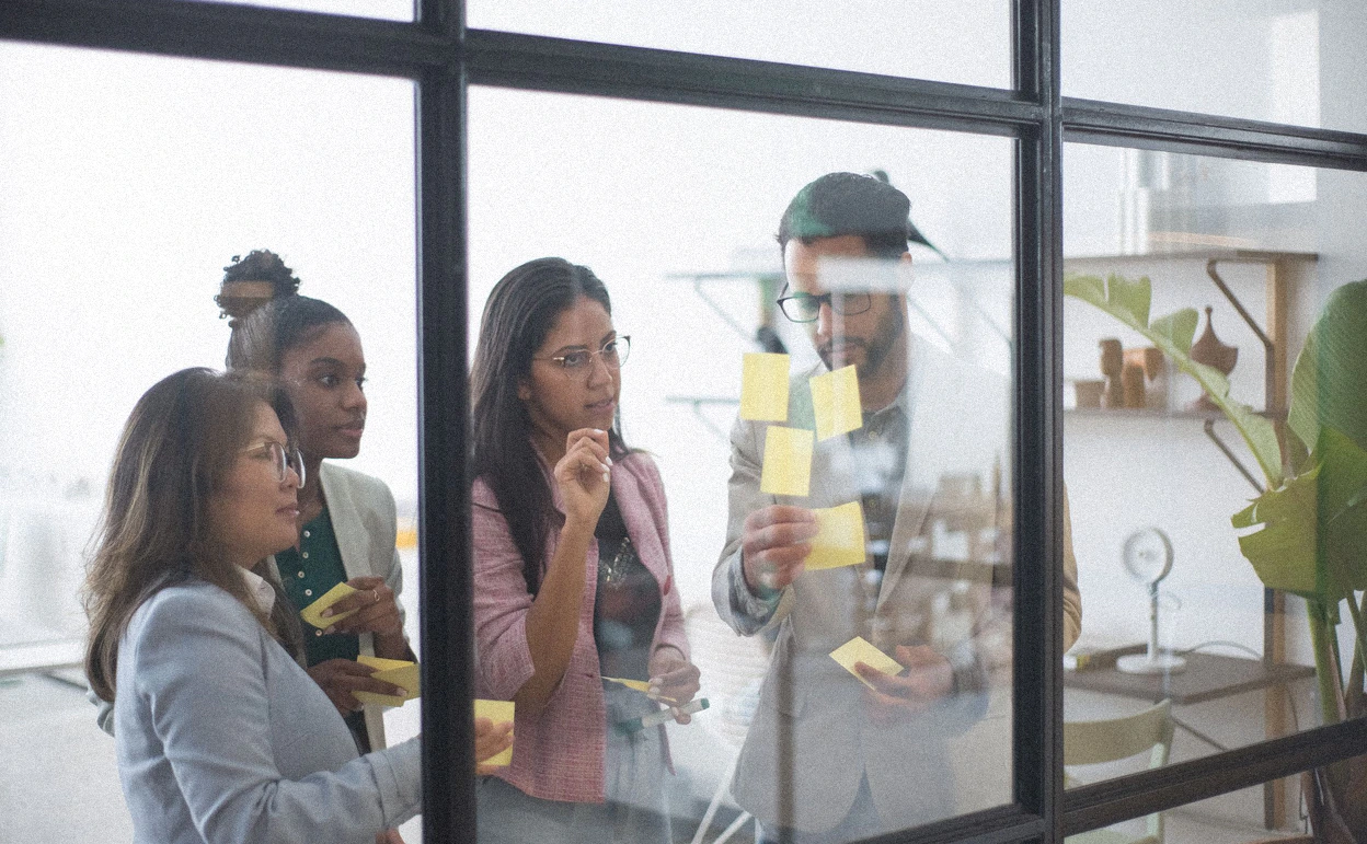 A change management workshop around a wall of sticky notes